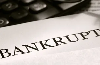 Cuvântul BANKRUPT este imprimat pe o foaie de hârtie lângă un calculator de masă.