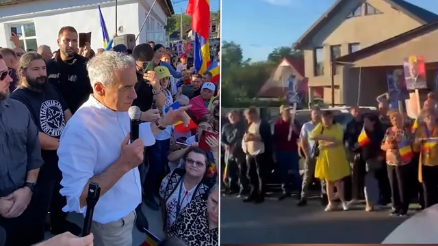 Un bărbat cu cămașă albă ține un microfon în fața unui grup de persoane strânse pe o stradă lângă clădiri.