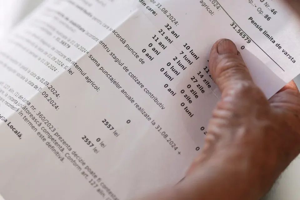 O mână ține un document tipărit cu detalii despre ani, luni, zile și sume de bani scrise în limba română.