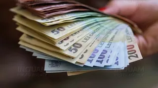 O mână ține un teanc de bancnote de diferite valori, inclusiv bancnote de cincizeci și două sute de lei.
