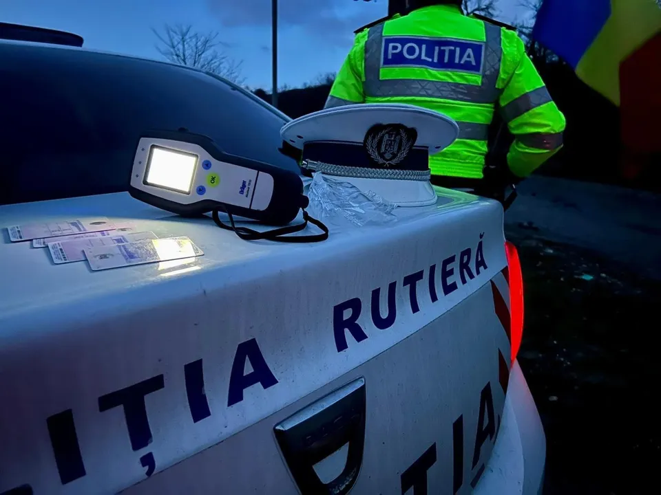 O cască albă de poliție și un aparat de testare alcolimetrică sunt așezate pe portbagajul unei mașini marcate cu textul poliția rutieră.
