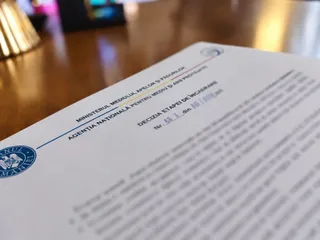 Un document oficial cu antetul Ministerului Mediului, Apelor și Pădurilor este așezat pe o suprafață de lemn întunecată.