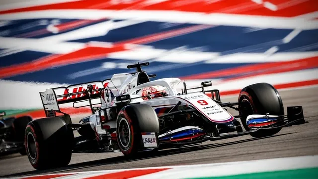 Un monopost de Formula 1 alb cu detalii roșii și negre circulă pe un circuit de curse.
