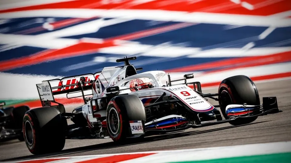 Un monopost de Formula 1 alb cu detalii roșii și negre circulă pe un circuit de curse.