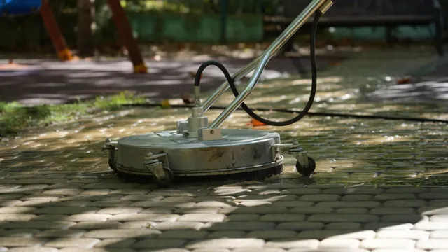 O mașină de spălat cu apă este poziționată pe un pavaj umed într-o zonă cu copaci în fundal.