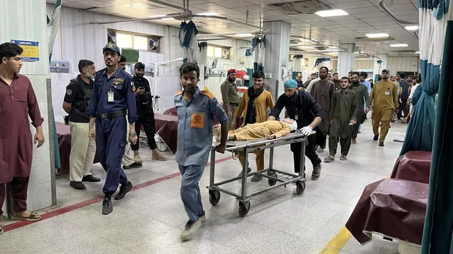 Un grup de bărbați transportă un pacient pe un cărucior de spital printr-un coridor de spital iluminat.