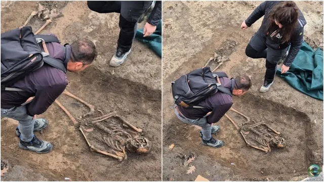 Două persoane privesc două schelete umane parțial îngropate în pământ pe un șantier.