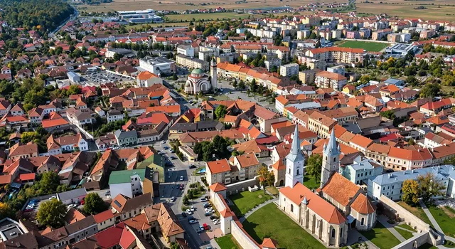O vedere aeriană a unui oraș cu numeroase clădiri cu acoperișuri de culoare roșie și câteva edificii cu turnuri înalte.
