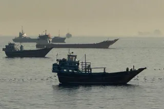 Mai multe nave de diferite dimensiuni navighează pe o suprafață de apă sub un cer înnorat și gri.