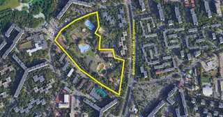 O vedere aeriană a unei zone urbane cu clădiri, copaci și o porțiune delimitată de o linie galbenă care conține câteva bazine de apă.