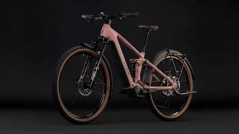 O bicicletă electrică de culoare roz este poziționată lateral pe un fundal negru.