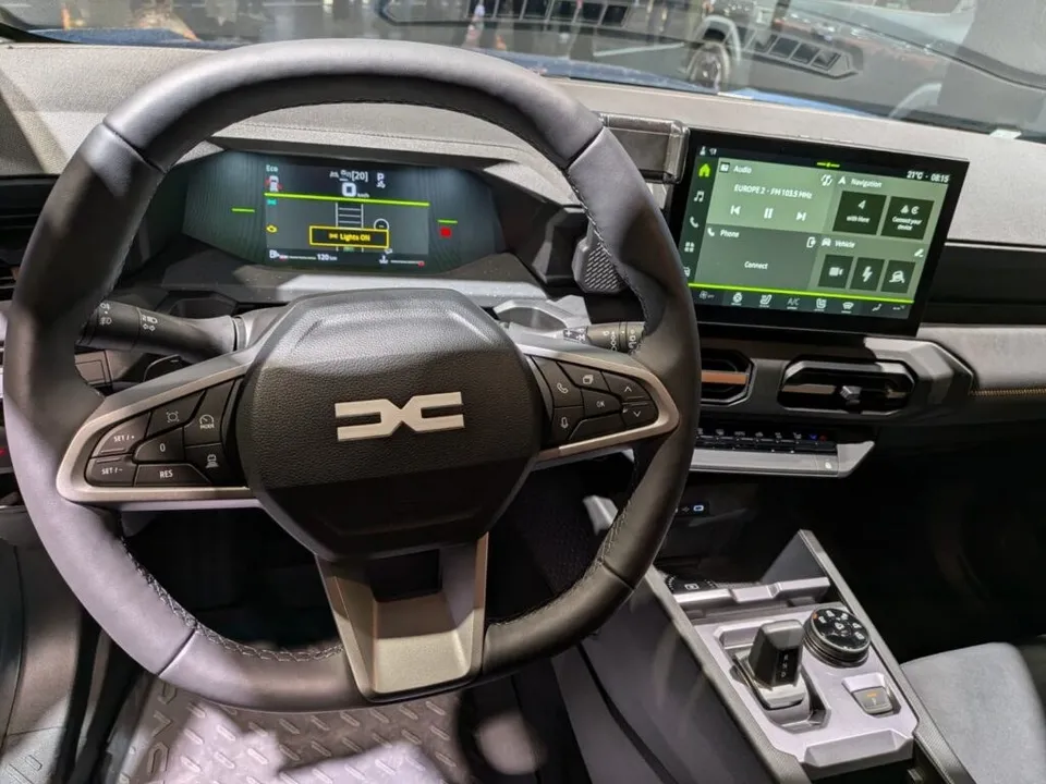 Interiorul unei mașini cu volanul negru, ecran digital și butoane de control pe consola centrală.