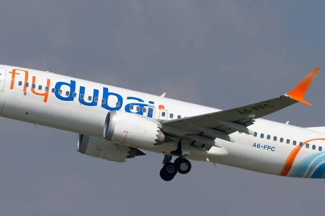 Un avion alb cu inscripția flydubai și marcajul A6-FPC zboară pe un cer gri.