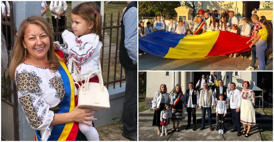 O femeie zâmbind poartă un copil îmbrăcat în cămașă tradițională, în timp ce un grup de oameni ține un steag mare colorat.