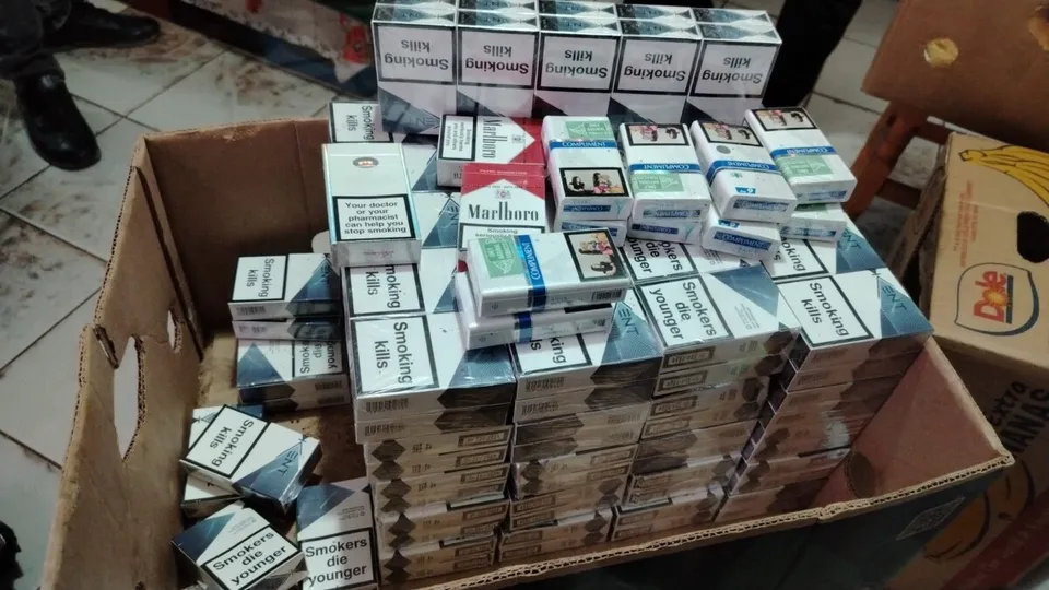 Multe pachete de țigări de diverse mărci sunt așezate în interiorul unui carton maro deschis.