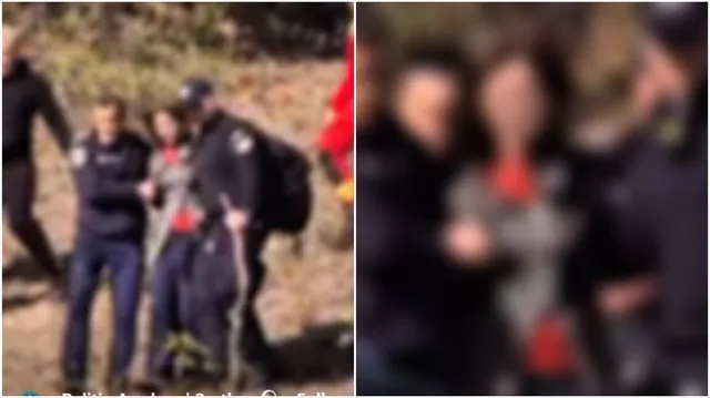 Un grup de persoane merge pe un teren împădurit, printre care un bărbat poartă un rucsac negru și un baston.