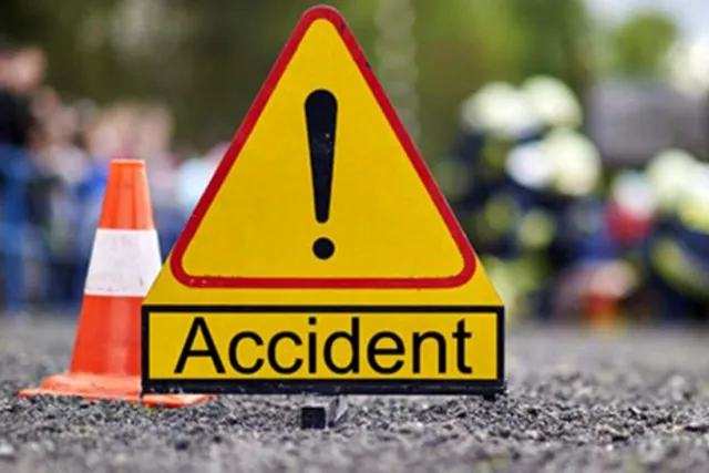 Un semn de avertizare triunghiular galben cu un semn exclamării negru și textul Accident este plasat pe asfalt lângă un con de circulație portocaliu.