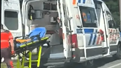 Interiorul unei ambulanțe cu ușile din spate deschise, prezentând o targă de transport medicală cu suport de culoare albastră și verde.