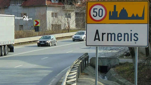 Un semn de circulație indică intrarea în localitatea Armeniș, având un indicator de limită de viteză de cincizeci și siluete de clădiri pe fundal galben.