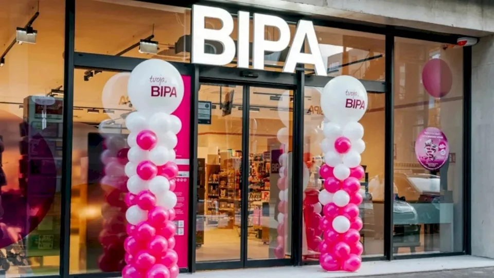 Fațada unui magazin BIPA este decorată cu coloane de baloane albe și roz lângă ușa de intrare din sticlă.