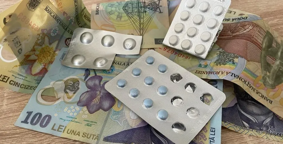 Mai multe blistere cu tablete albe sunt așezate peste diverse bancnote românești pe o suprafață de lemn.