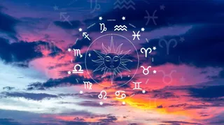 Simbolurile zodiacului sunt dispuse într-un cerc în jurul unei reprezentări a soarelui pe un fundal de cer cu nori colorați la apus.