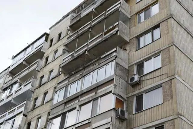 O clădire de apartamente cu balcoane și ferestre cu cadre albe, având unități de aer condiționat montate pe fațadă.