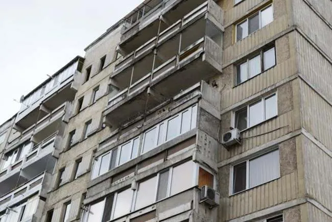 O clădire de apartamente cu balcoane și ferestre cu cadre albe, având unități de aer condiționat montate pe fațadă.
