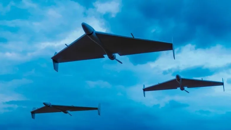 Trei aeronave fără pilot zboară prin cerul de culoare albastră sub un nor de nori.
