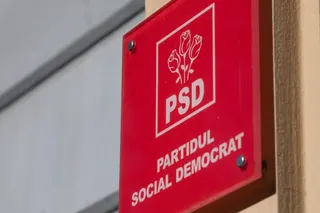 Un semn roșu dreptunghiular pe un perete afișează logo-ul PSD și textul PARTIDUL SOCIAL DEMOCRAT.