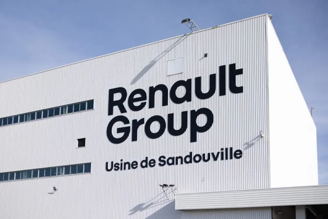 O clădire albă cu textul Renault Group și Usine de Sandouville pe fațada sa sub un cer senin.