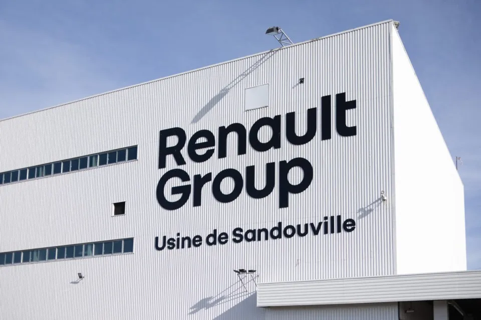 O clădire albă cu textul Renault Group și Usine de Sandouville pe fațada sa sub un cer senin.