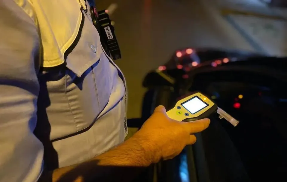 O persoană în uniformă ține un aparat de testare digital cu un ecran luminos în mână.