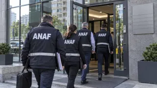 Patru persoane purtând veste vestimentare cu inscripția ANAF merg spre intrarea unei clădiri moderne.
