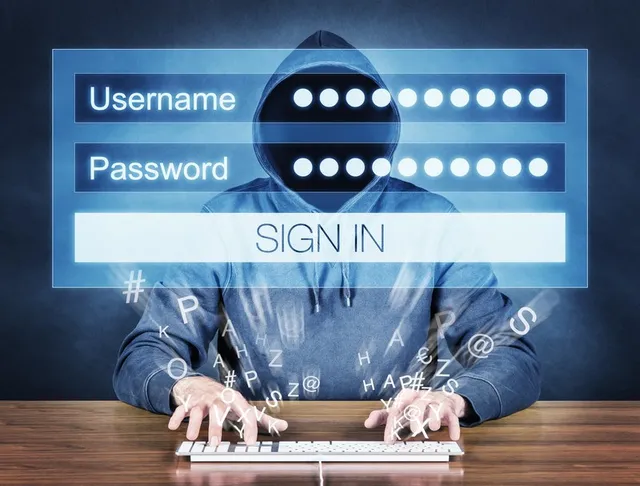 O persoană purtând o hanorac cu glugă și fața acoperită stă la un tastatură de calculator în fața unui panou de autentificare digital.
