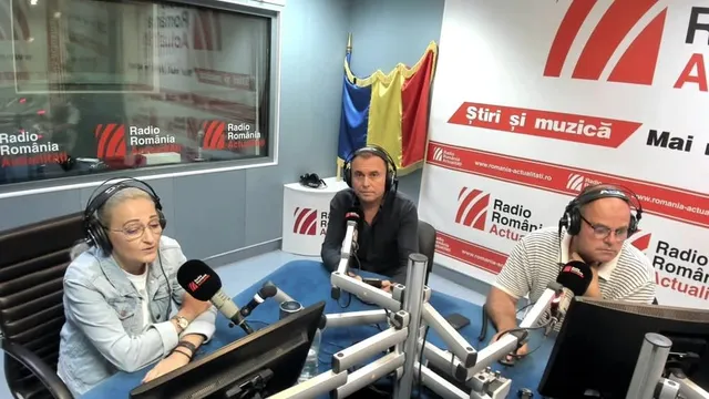 Trei persoane cu căști de ascultare stau la mese cu microfoane într-un studio de radio.