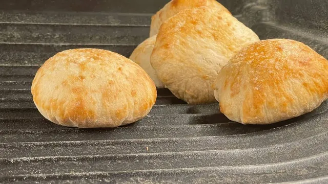 Câteva produse de panificație rotunde și aurii sunt așezate pe o suprafață gri cu strii paralele.