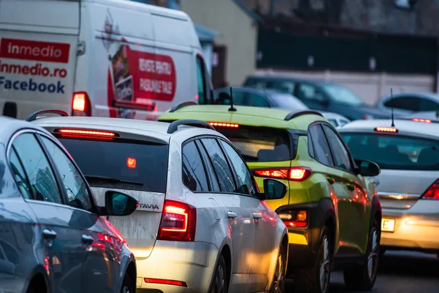 Mai multe mașini colorate sunt așezate în trafic pe un drum urban.