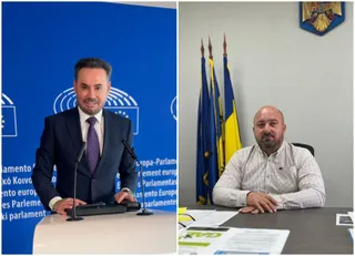 Un bărbat în costum și cravată stă în spatele unui podium, iar un alt bărbat în cămașă stă la o masă lângă trei steaguri.