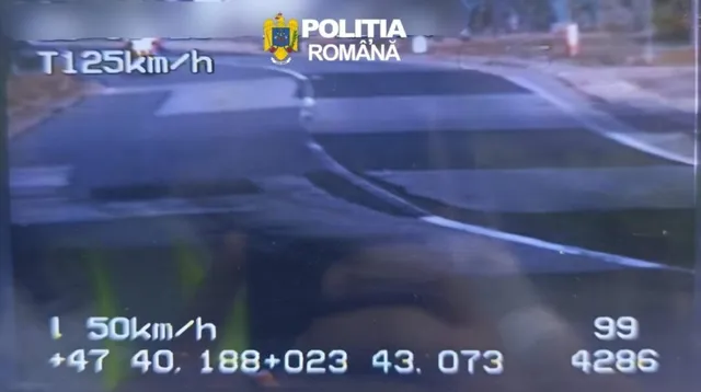 O imagine de pe un ecran de radar afișează viteza de 125 km/h pe o porțiune de drum asfaltat cu marcaje albe.