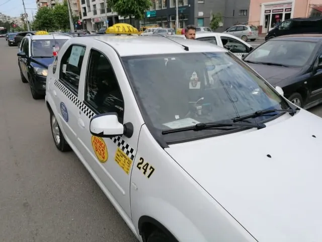 Un taxi alb cu numărul 247 și un semn galben pe plafon este parcat pe o stradă lângă alte mașini.