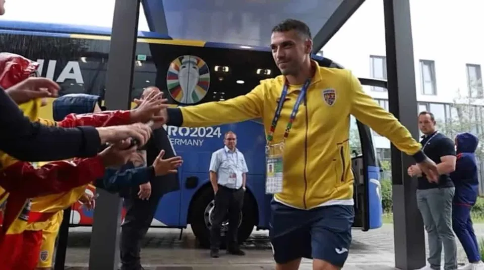 Un bărbat într-un tricou galben și pantaloni scurți de sport se întinde spre mai mulți oameni de pe partea stângă a imaginii.