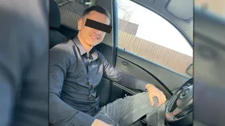 Un bărbat cu o cămașă gri și pantaloni deschiși la genunchi stă așezat pe scaunul pasagerului într-un autoturism.