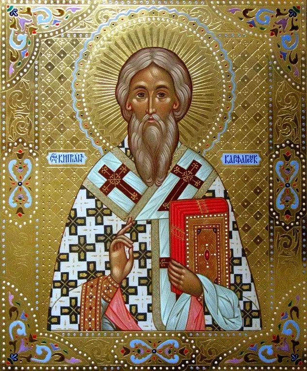 O icoană aurie reprezintă un bărbat cu barbă lungă, purtând haine liturgice și ținând o carte roșie decorată.
