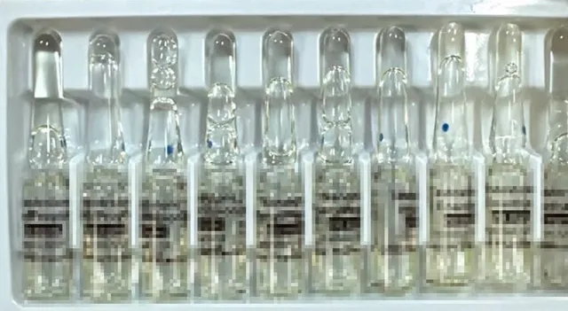 O serie de ampule de sticlă transparente cu lichid sunt așezate într-un suport de plastic alb.