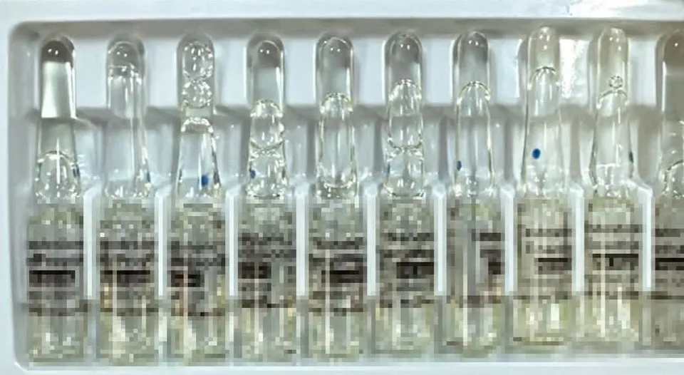 O serie de ampule de sticlă transparente cu lichid sunt așezate într-un suport de plastic alb.