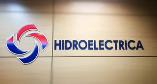 Un logo roșu și albastru este montat pe un perete de culoare deschisă lângă textul scris cu litere de culoare albastră.
