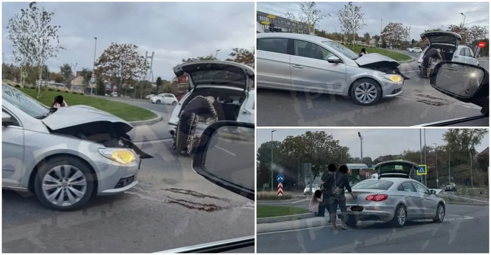 Două autoturisme gri sunt oprite pe asfaltul unei străzi, unul având capota ridicată și celălalt portbagajul deschis, lângă un sens giratoriu.