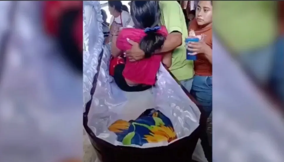 O persoană în haine roz îmbrățișează o altă persoană care stă în interiorul unui obiect căptușit cu material alb.