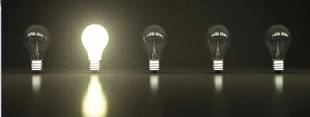 Cinci becuri sunt așezate într-un rând pe o suprafață întunecată, dintre acestea unul este aprins și emite o lumină puternică.